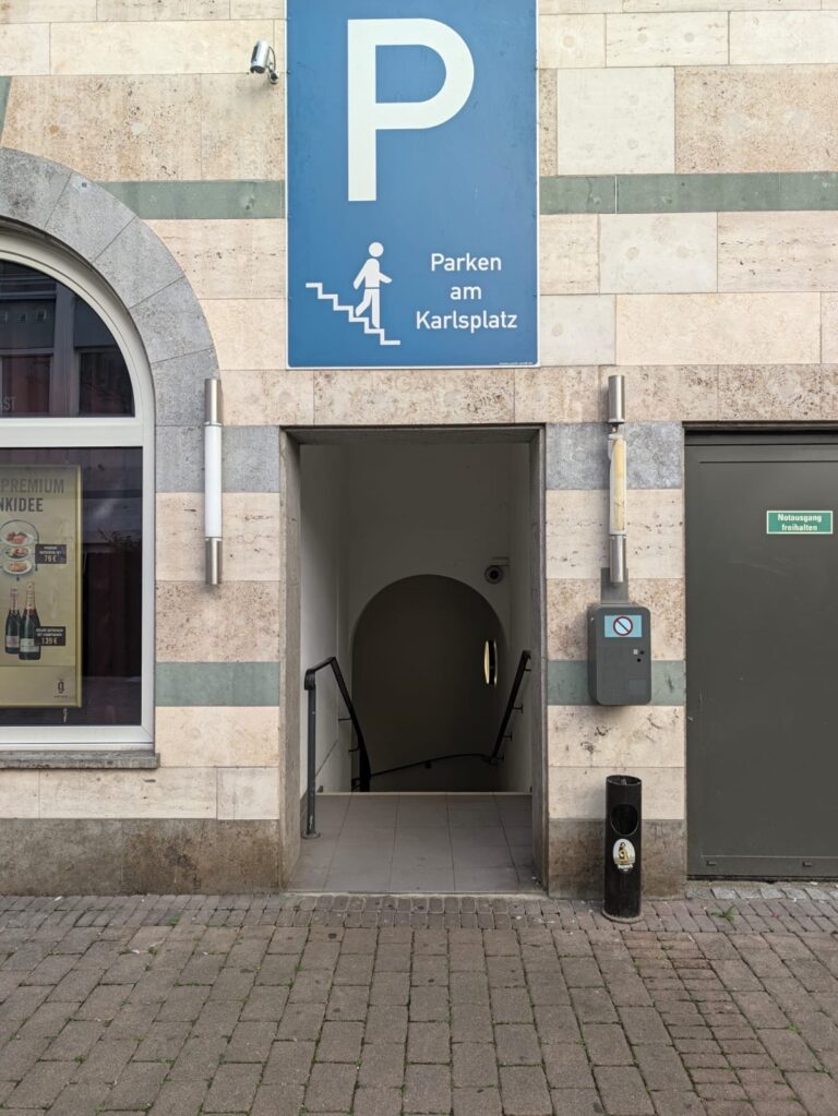 Treppenhaus neben dem Gloria Kino mit Schild „Parken am Karlsplatz“